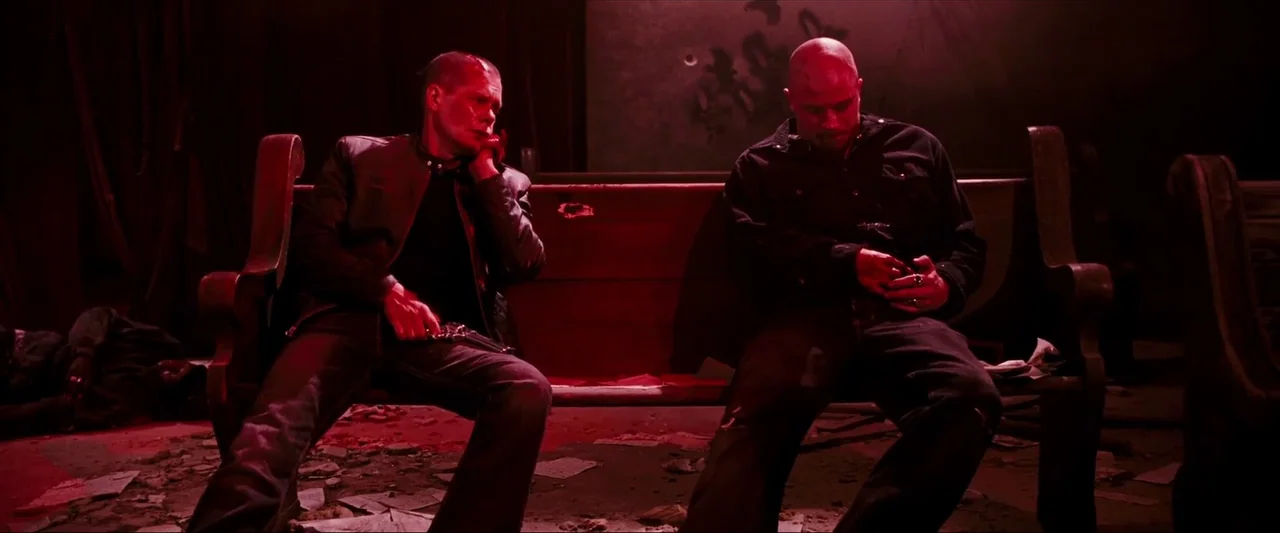 Death Sentence (2007) movie still: fullbody — A dark, dilapidated space with debris scattered on the floor and a wooden pew. Two men sit on the…