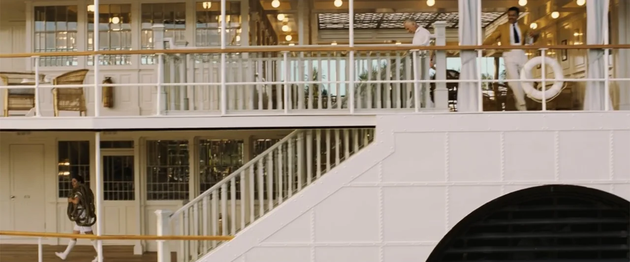 Death on the Nile (2022) movie still: wide — The exterior deck of a multi-level white passenger ship features ornate wooden railings and stairs. A…