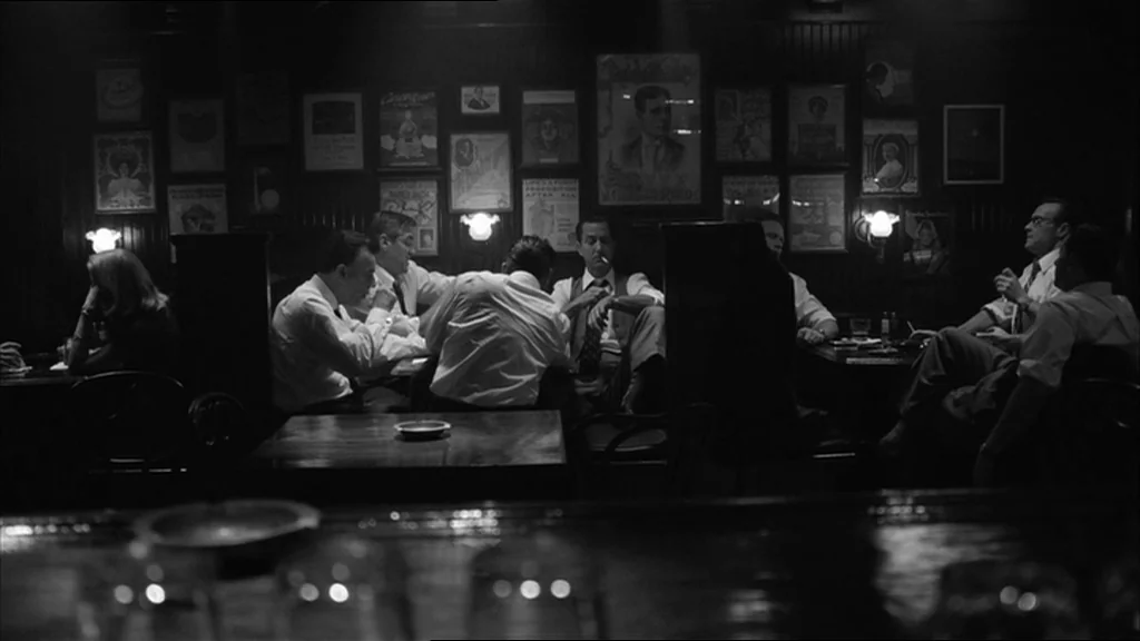 Good Night And Good Luck (2005) movie still: wide — A dimly lit tavern with dark wood paneled walls decorated with vintage posters. Several men in…