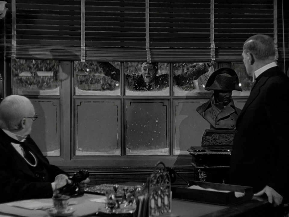 It’s A Wonderful Life (1946) movie still: medium — A dark office setting features two men at a desk facing a window. A man is visible through the…