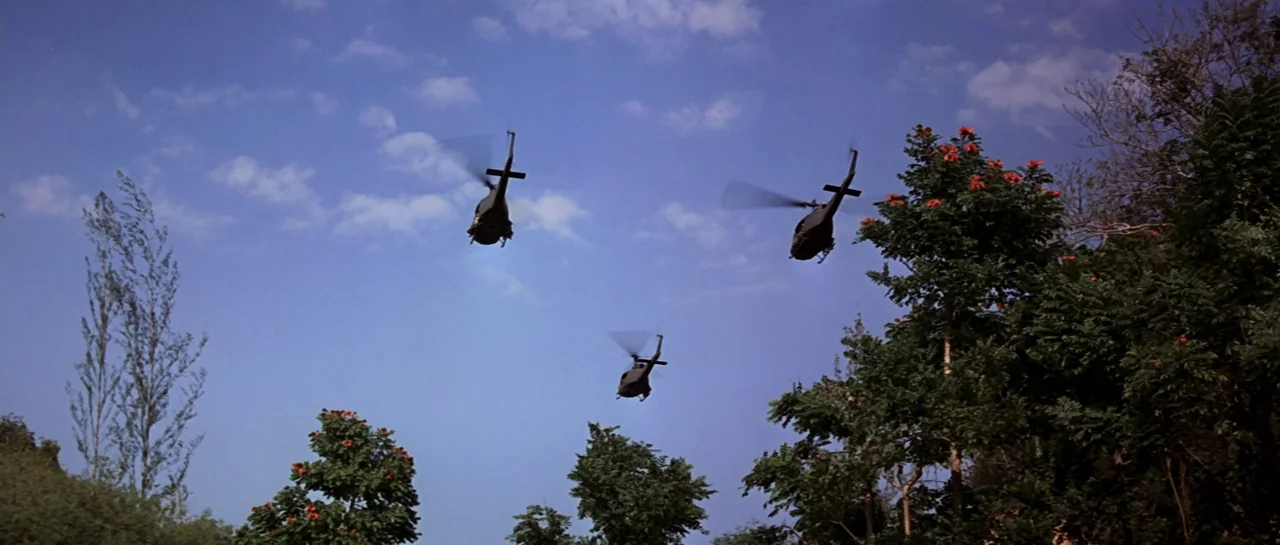 GoldenEye (1995) movie still: wide — Three military helicopters fly in formation over a dense tropical landscape under a blue sky. The aircraft are…