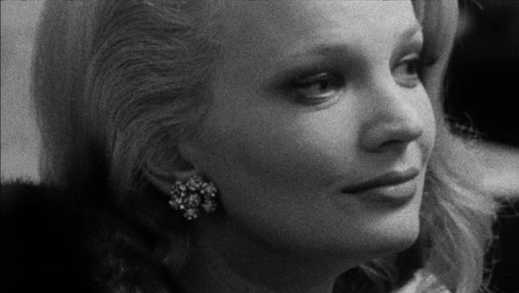 Faces (1968) movie still: closeup — A woman is captured in a tight closeup against an out-of-focus background. She looks toward the side while…