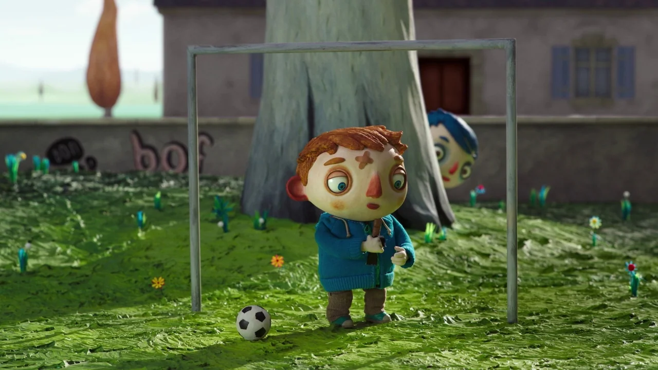My Life as a Zucchini (2016) movie still: medium — A clay-textured playground features a small boy standing near a metal soccer goal. A second boy…