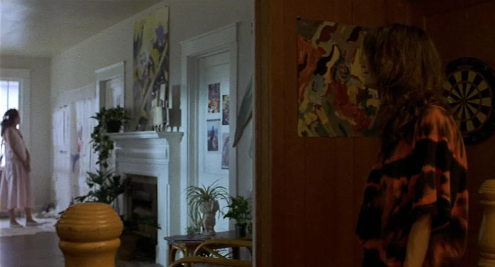 Sex, Lies And Videotape movie still: medium — A residential living room contains a white fireplace mantel adorned with potted green plants. A woman…