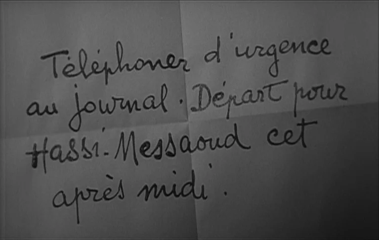 Le Signe du Lion (1962) movie still: closeup — A folded piece of paper features cursive handwriting in dark ink on a light surface. The text reads…