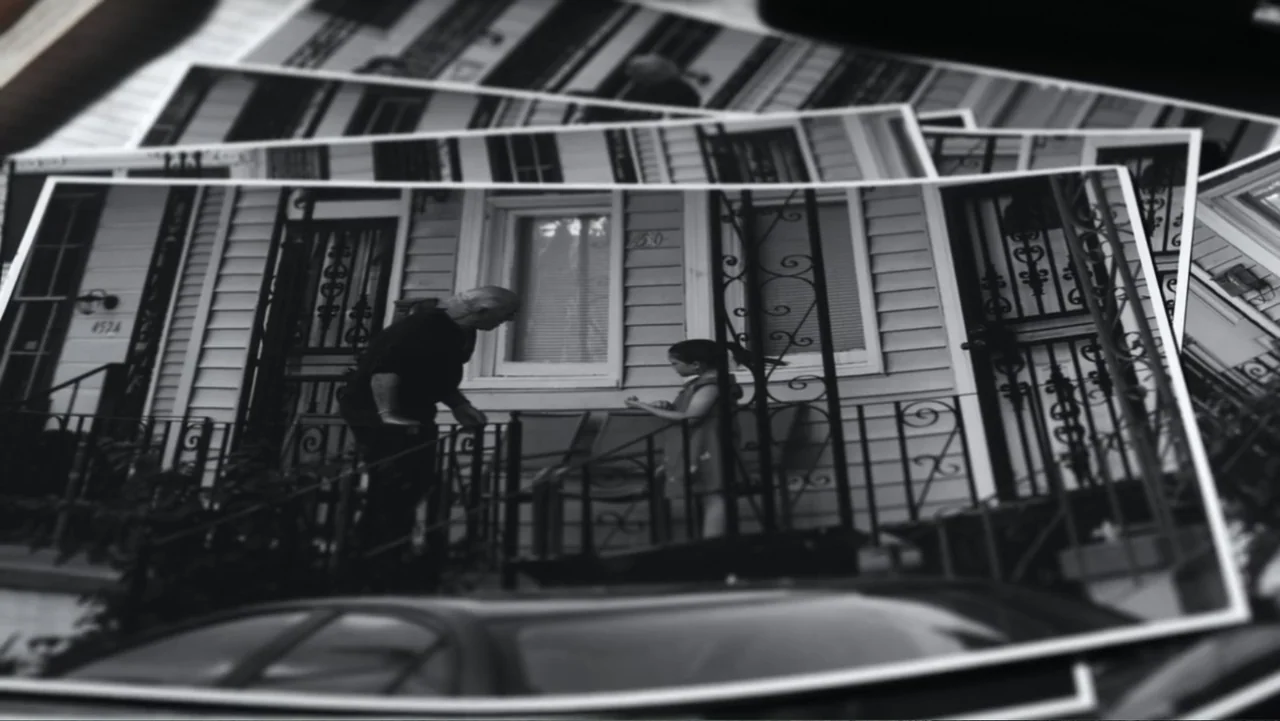 The Messenger (2015) movie still: medium — A residential stoop features wrought iron railings in front of a wood-sided building. An older man and a…