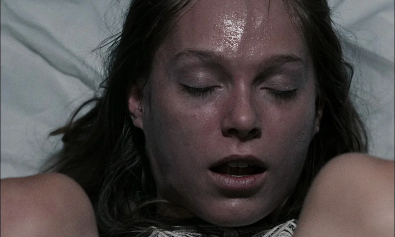 The Third Part of the Night (1971) movie still: closeup — A close-up of a woman lying down on a white surface. She has sweat on her forehead and her…