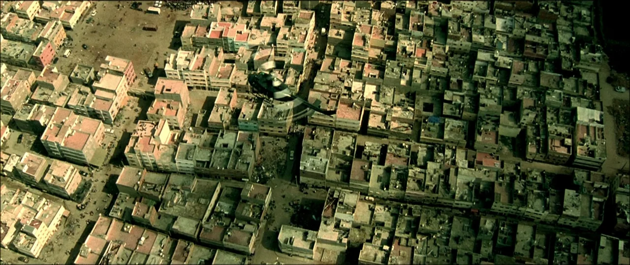 Black Hawk Down (2001) movie still: establishing — A dense urban landscape consists of flat-roofed concrete buildings packed tightly together. A…