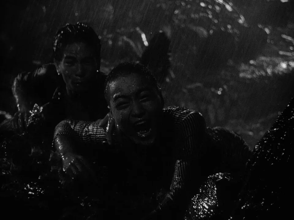 Godzilla (1954) (1954) movie still: medium — Two people crawl through a dark, rain-drenched field covered in mud. The woman shouts while moving…