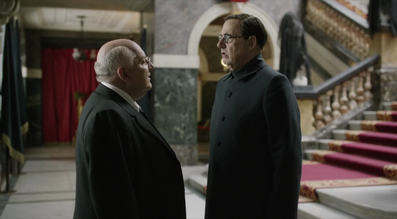 The Death of Stalin (2017) movie still: medium — An opulent building interior features a marble staircase with red carpeting and arched doorways.…