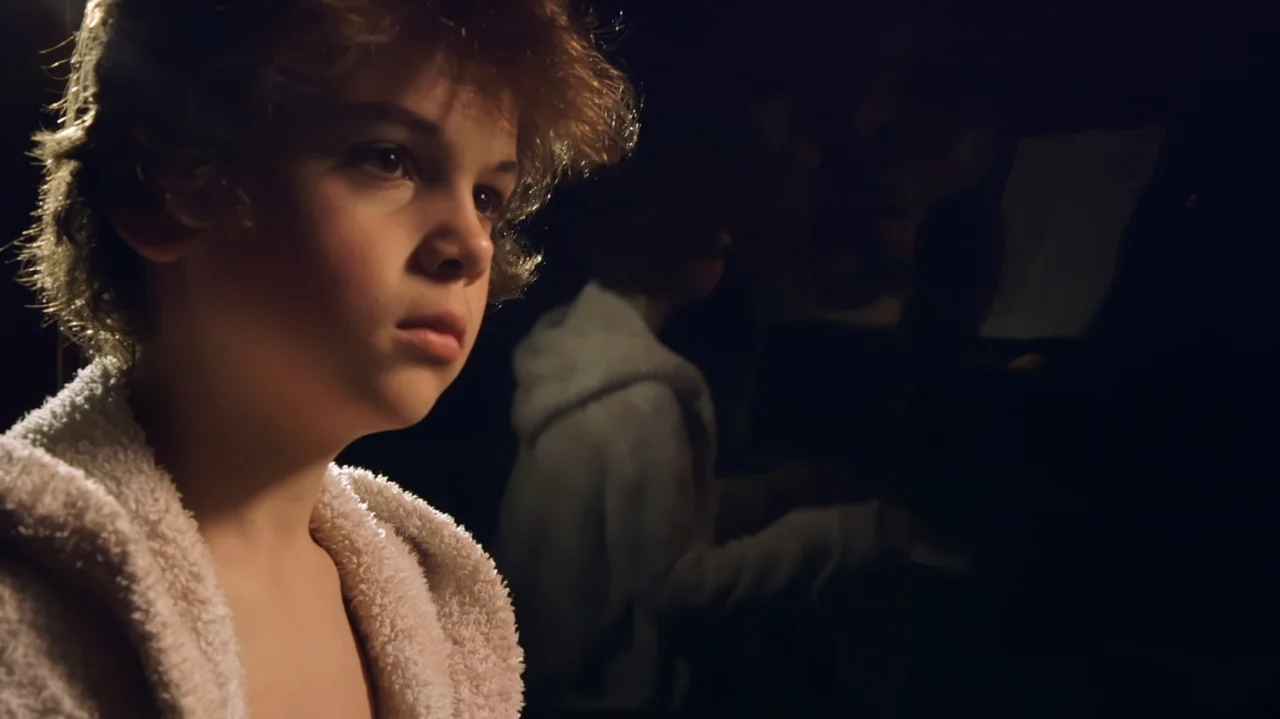 Moonlight Sonata: Deafness in Three Movements (2019) movie still: closeup — An interior dimly lit space featuring a child in a bathrobe. The child…