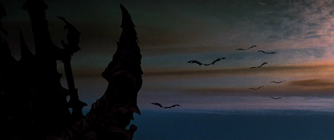 The Dark Crystal (1982) movie still: establishing — A dark gothic spire rises in the foreground against a dim, overcast sunset sky. Several bats fly…
