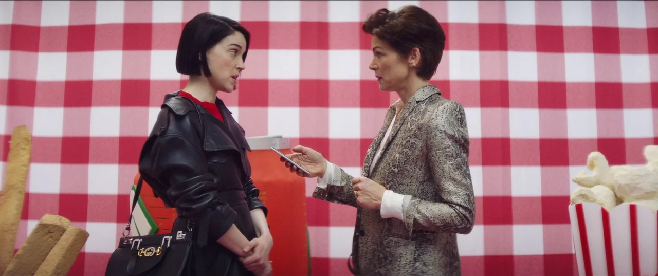 The Nowhere Inn (2020) movie still: medium — A studio set features a large red and white gingham backdrop with oversized props. Two women stand…