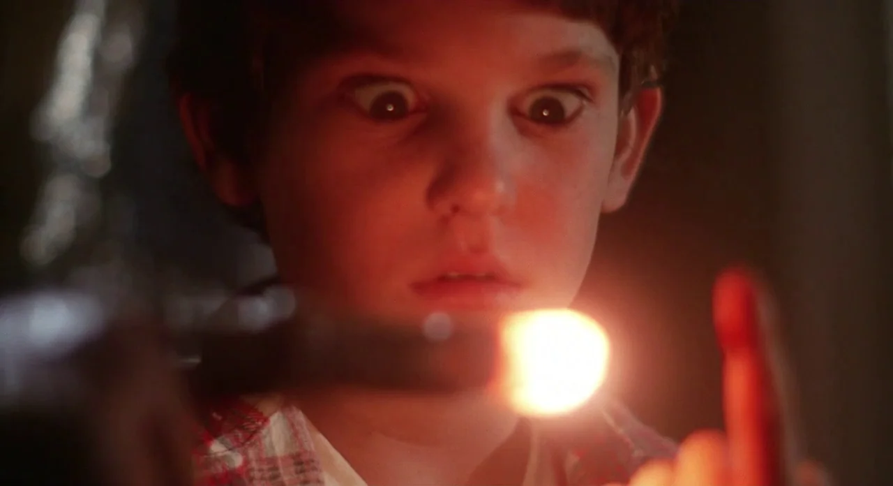 E.T. The Extra-Terrestrial (1982) movie still: closeup — A close-up shot of a young boy illuminated by a glowing object at night. The light source…