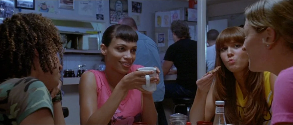 Death Proof movie still: medium — A diner booth occupied by three young women engaged in conversation over breakfast. The background shows diner…