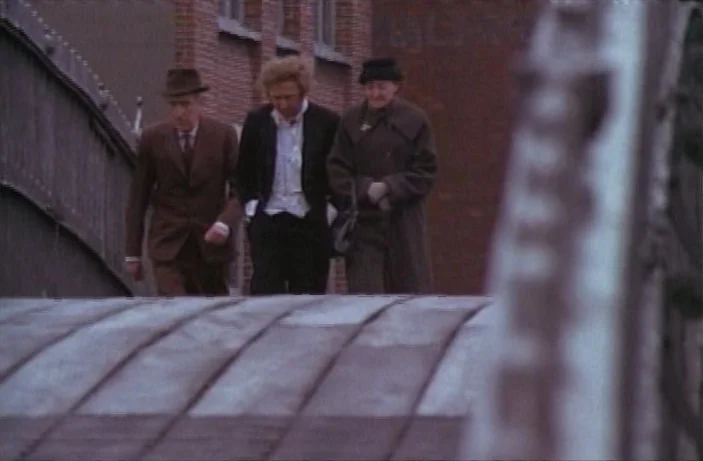 Quackser Fortune Has a Cousin in the Bronx (1970) movie still: fullbody — A metal arched bridge leads toward a brick building exterior during the…