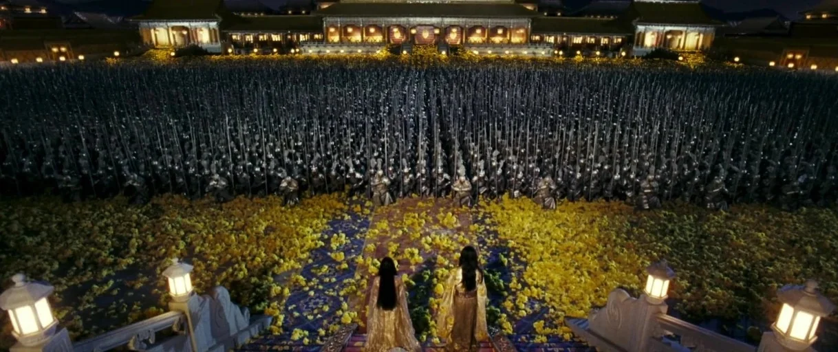 Curse of the Golden Flower (2006) movie still: wide — A vast courtyard is covered in yellow flowers before a massive traditional palace structure.…
