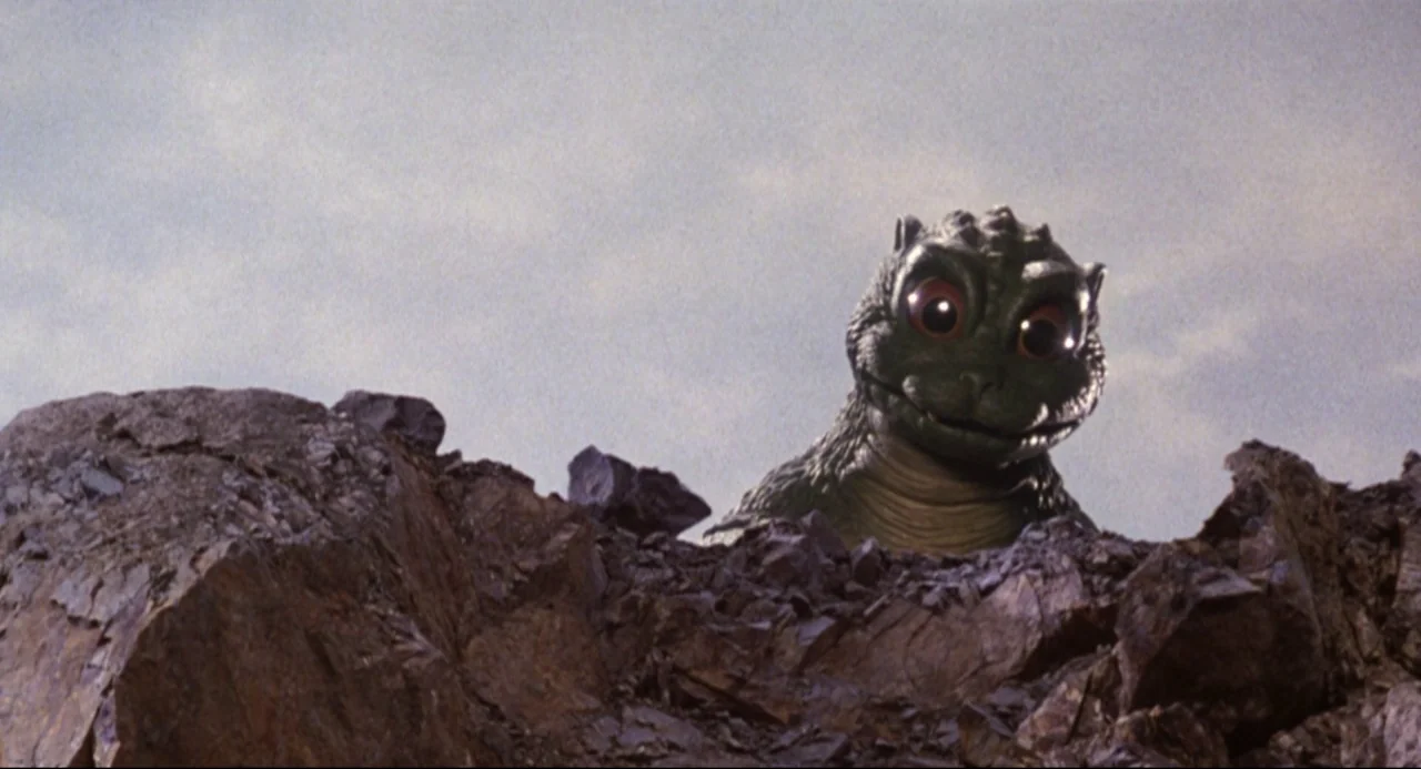 Godzilla vs. SpaceGodzilla (1994) movie still: medium — A rocky, barren landscape featuring large jagged stones under a light sky. A reptilian…
