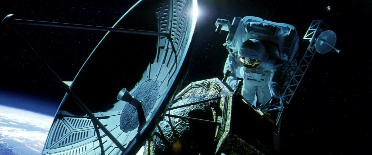 Armageddon (1998) movie still: wide — A satellite dish floats in deep space with the earth visible on the horizon. An astronaut in a white suit…
