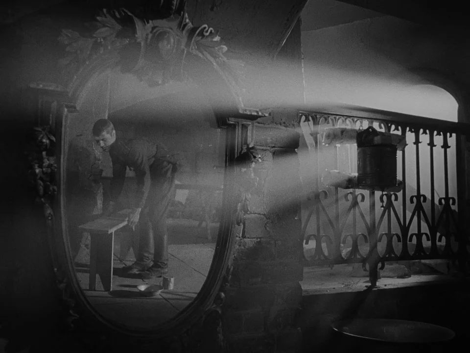 Ivan’s Childhood (1962) movie still: medium — A sparse, dimly lit stone cell features an ornate mirror reflecting the interior. A young man in…