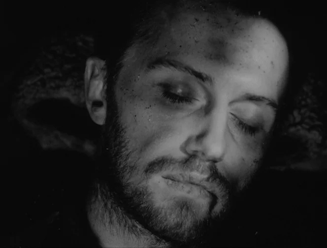 The Ascent (1977) movie still: closeup — A man's face is illuminated in extreme close-up against an entirely dark background. He has his eyes closed…