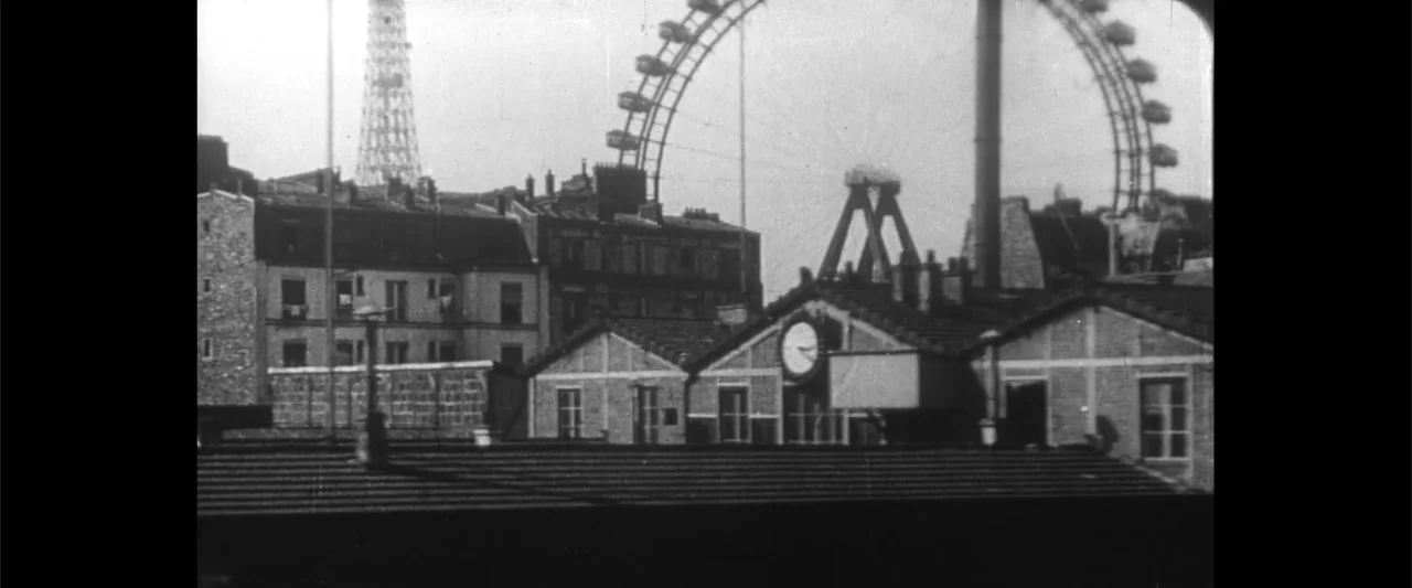 Jules and Jim (1962) movie still: wide — A view of dense city buildings with a large ferris wheel in the background. The scene includes a clock on…