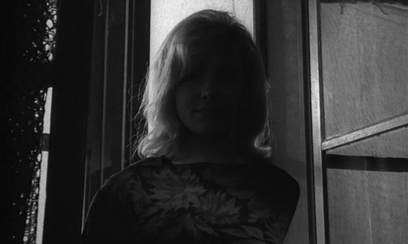Man Is Not Bird (1965) movie still: medium — A woman stands indoors in front of a window that provides strong backlighting. The scene is captured in…
