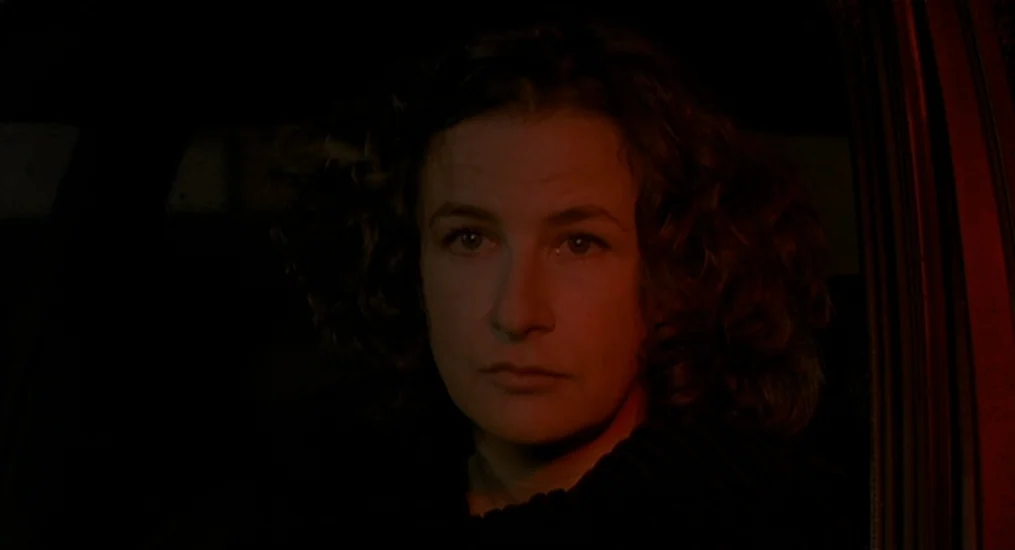 Vendredi Soir (2002) movie still: closeup — A woman sits inside a dark car illuminated by a faint red light. She looks directly ahead through the…