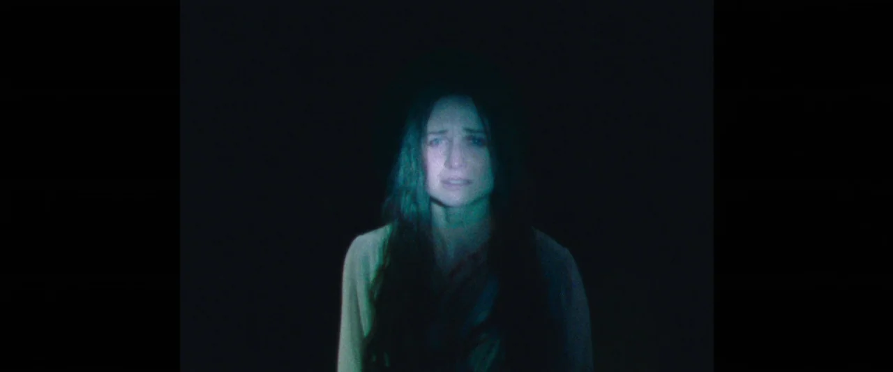 Censor (2021) movie still: medium — A woman is centered in a pitch-black, undefined void. She appears to be illuminated by a single, soft, cold…