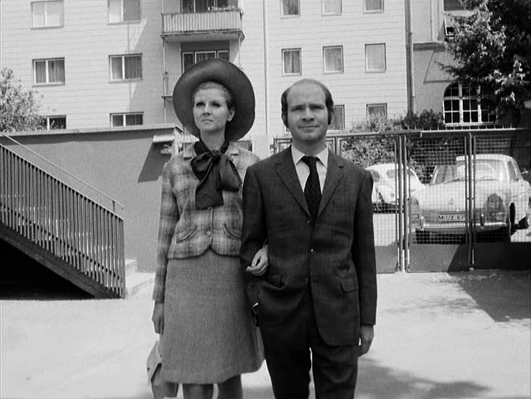 Katzelmacher (1969) movie still: fullbody — A modern apartment complex exterior with multi-story balconies and a metal staircase visible. A…