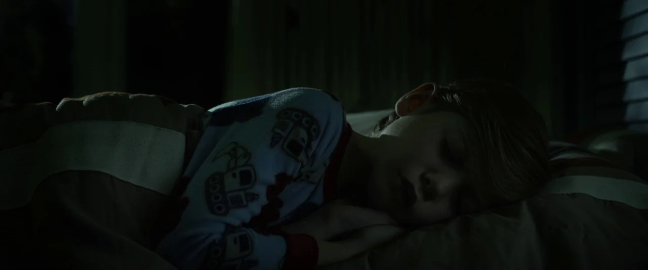 Before I Wake (2016) movie still: closeup — A dimly lit room at night features a young boy lying on a pillow. The child is asleep, facing the side…