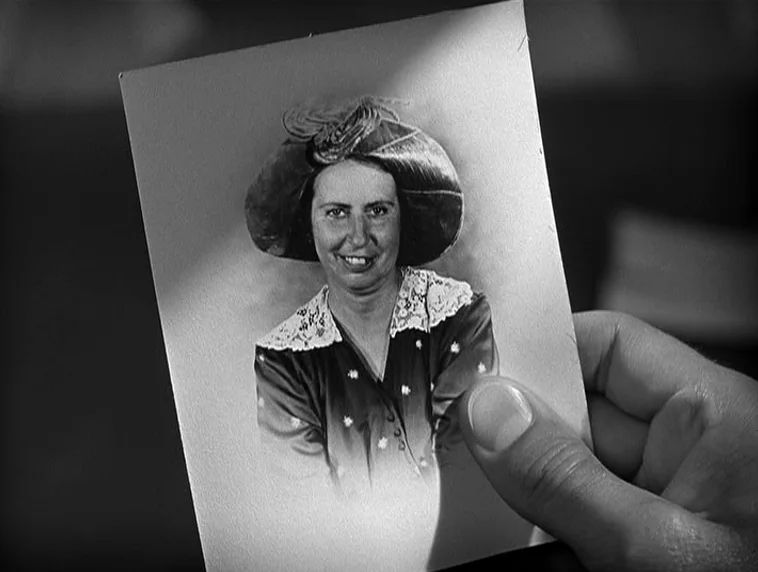 The Roaring Twenties (1939) movie still: closeup — A close-up view of a hand holding a black and white portrait photograph. The image depicts a…