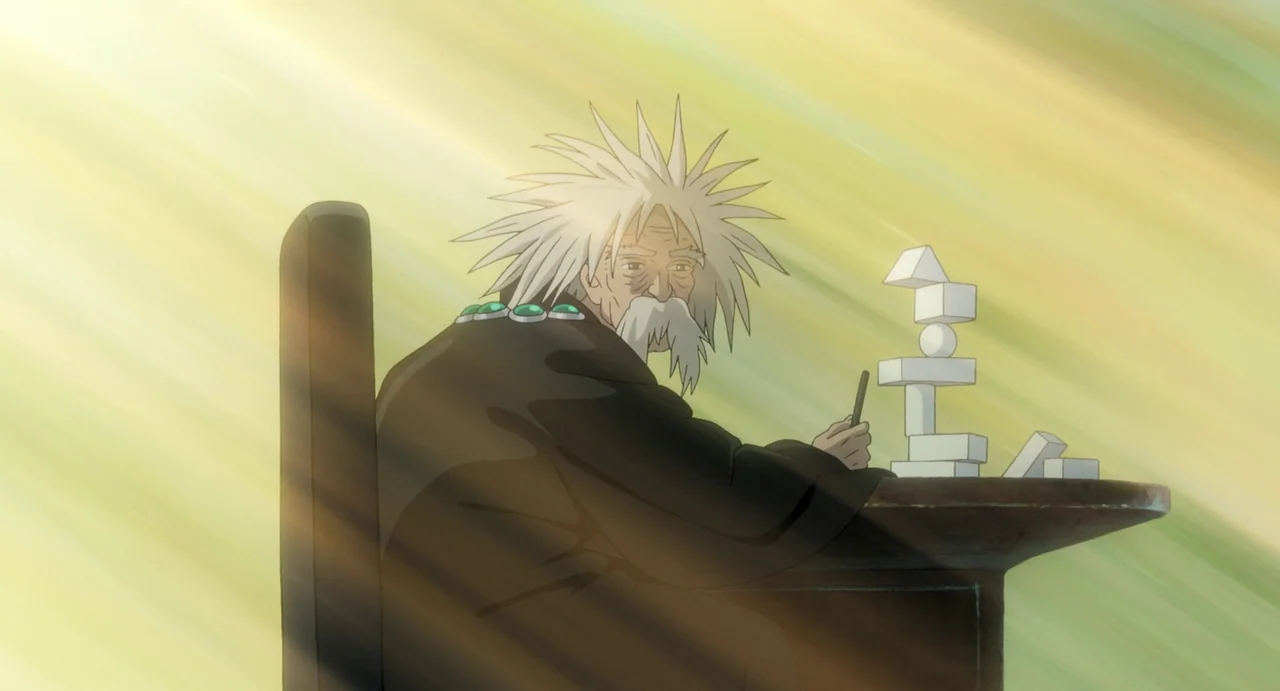 The Boy and The Heron (2023) movie still: medium — An elderly man with spiky white hair sits at a desk in a bright room. He works on stacking white…