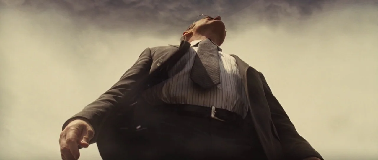 Thor (2011) movie still: medium — An open outdoor space under a pale, overcast sky. An older man in a business suit stands alone looking up.