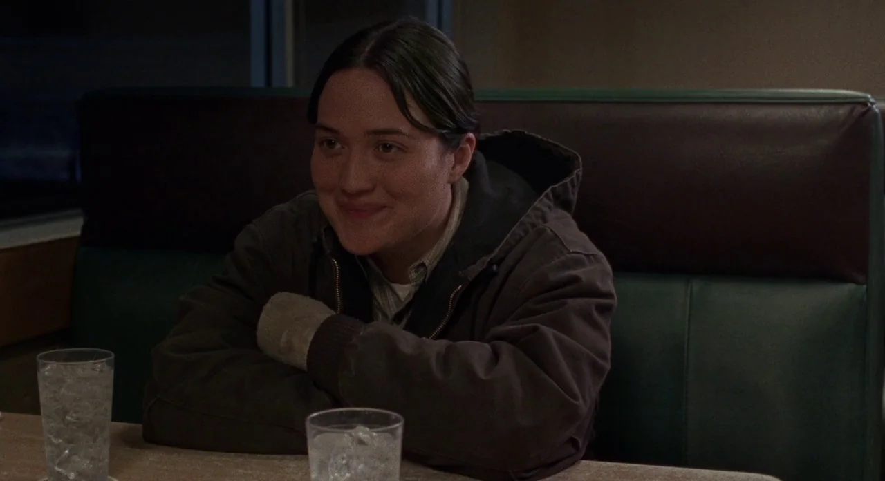 Certain Women (2016) movie still: medium — A person sits in a booth at a diner with green vinyl seats. The subject sits at a table with two glasses…