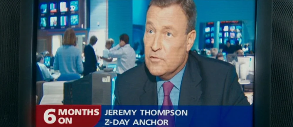 Shaun Of The Dead (2004) movie still: medium — A news broadcast showing a male anchor seated in a busy newsroom studio. Behind him, other…