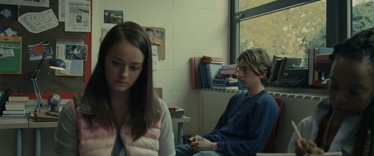 Chemical Hearts (2020) movie still: medium — A high school interior with beige brick walls and a window overlooking greenery. Three teenagers are…