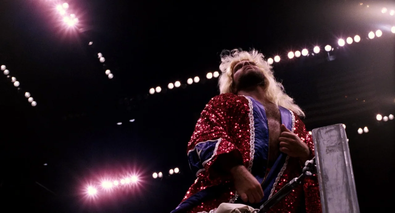Highlander (1986) movie still: medium — An indoor wrestling ring is illuminated by high overhead stadium lights against black darkness. A muscular…
