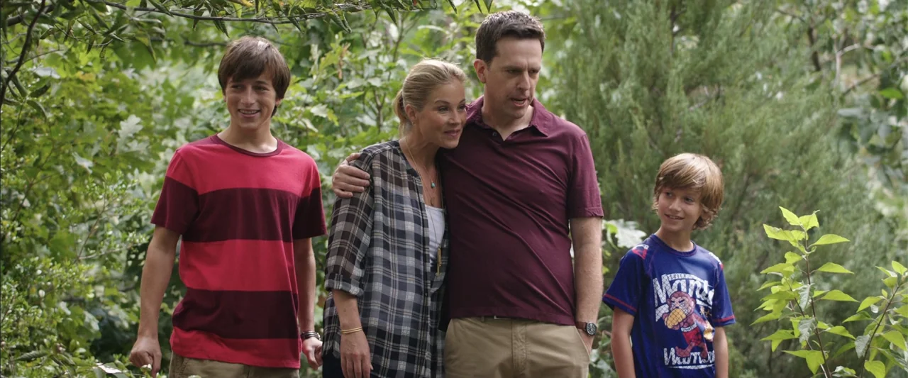 Vacation (2015) movie still: fullbody — A dense patch of green trees and bushes forms the backdrop for the people. Four family members stand…