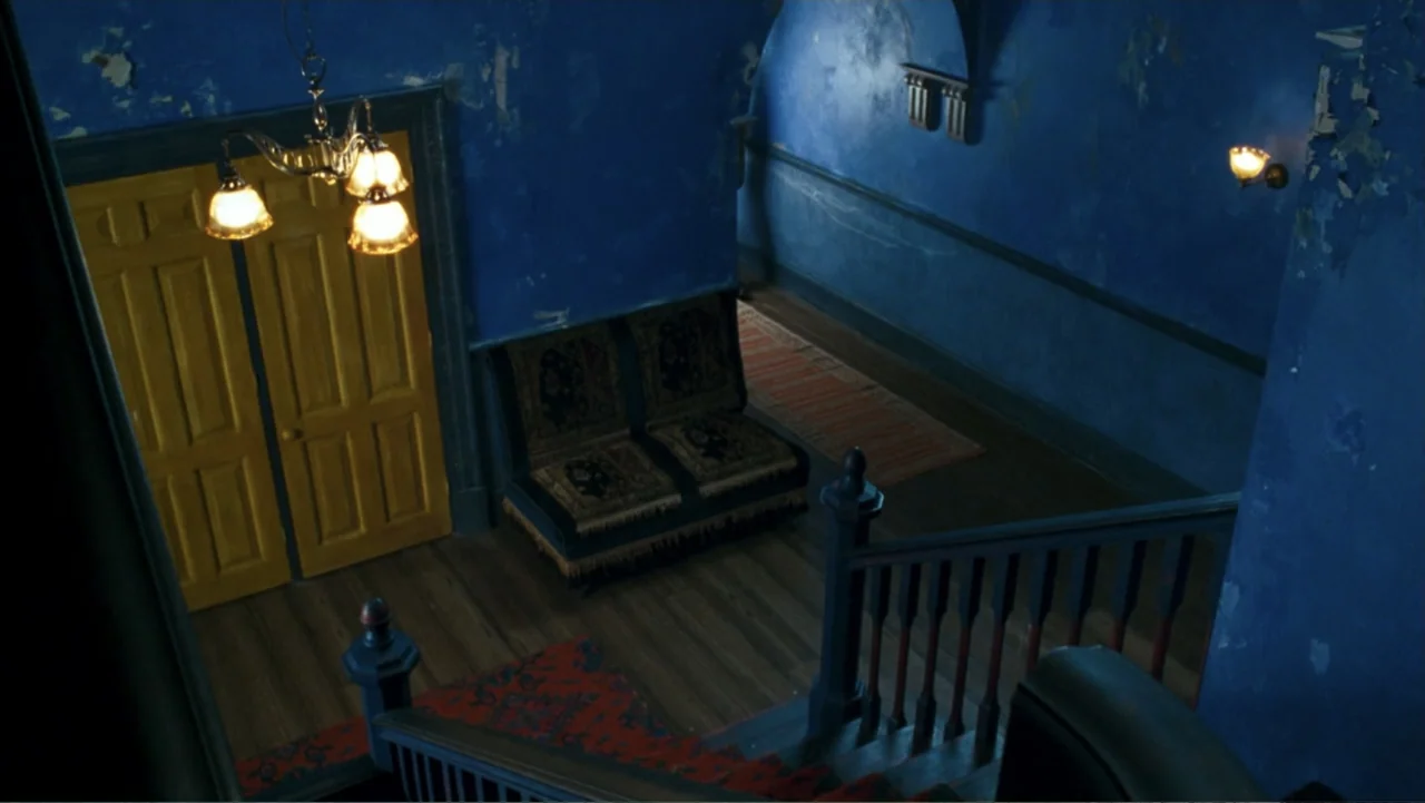 Nanny McPhee and the Big Bang (2010) movie still: establishing — A high-angle view looks down upon a dark blue landing with a wooden banister. A…