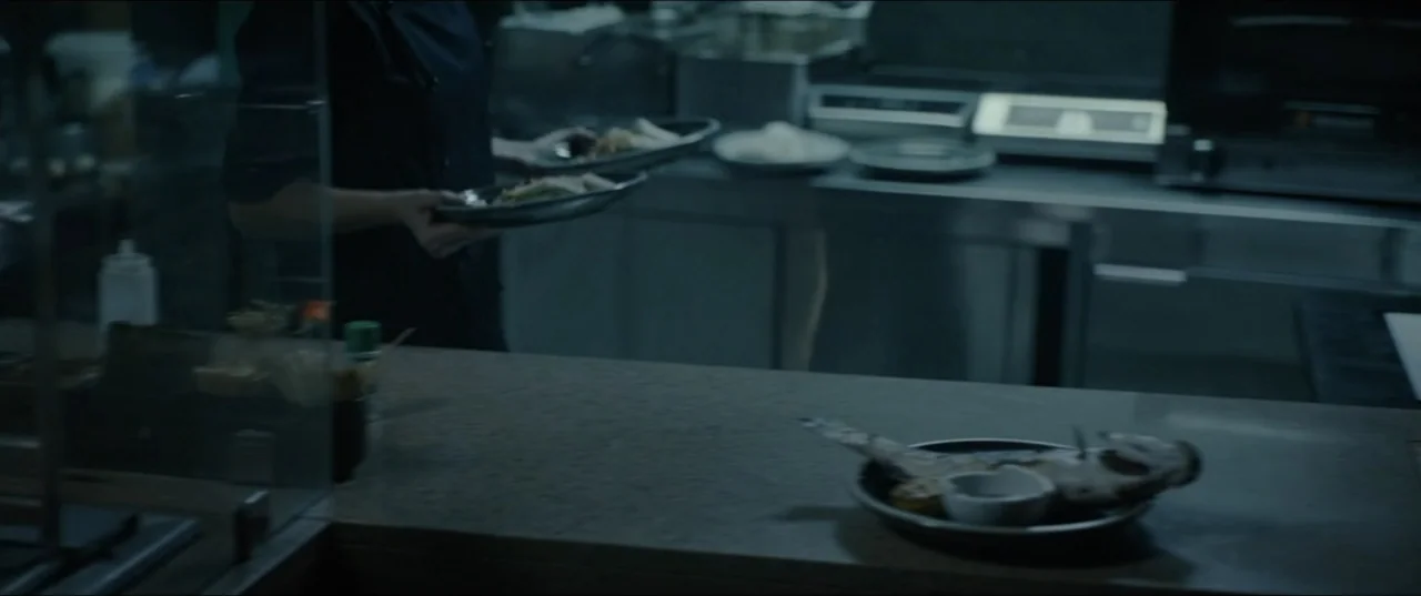 Dogs Don't Wear Pants (2019) movie still: medium — A professional kitchen features stainless steel surfaces and a cluttered preparation counter. A…