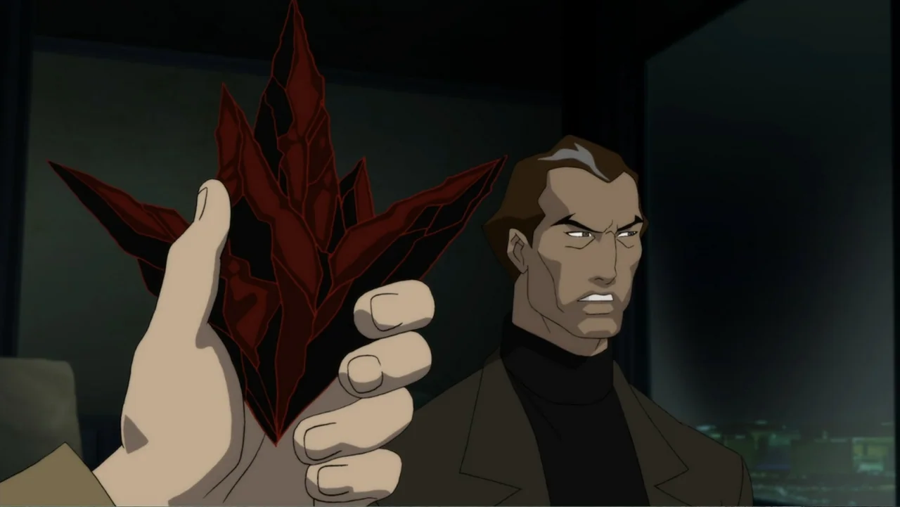 Justice League Dark (2017) movie still: medium — An dimly lit interior room at night features a dark desk area in background. A hand in the…