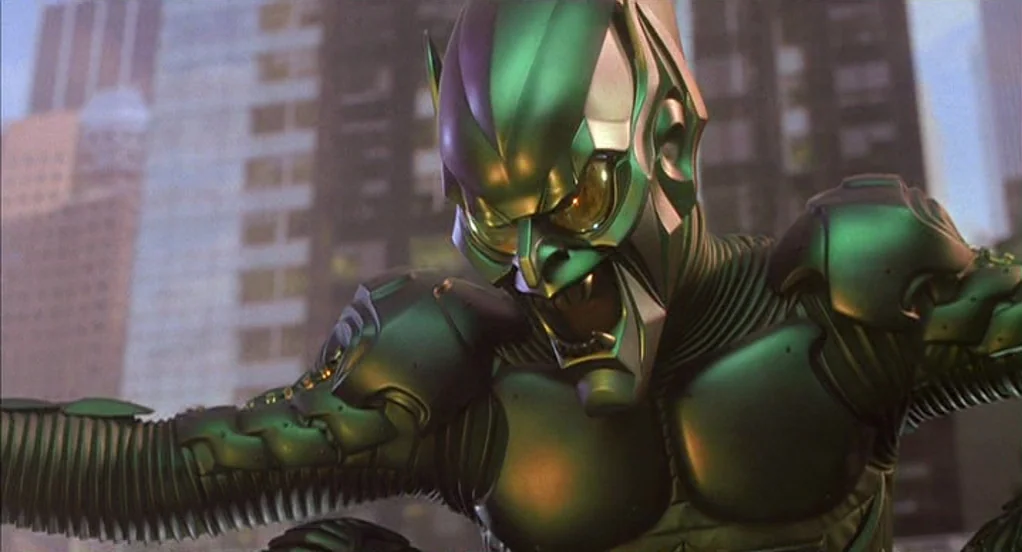 Spider-Man (2002) movie still: medium — A close perspective of a character in a green metallic armored suit against tall buildings. The figure leans…