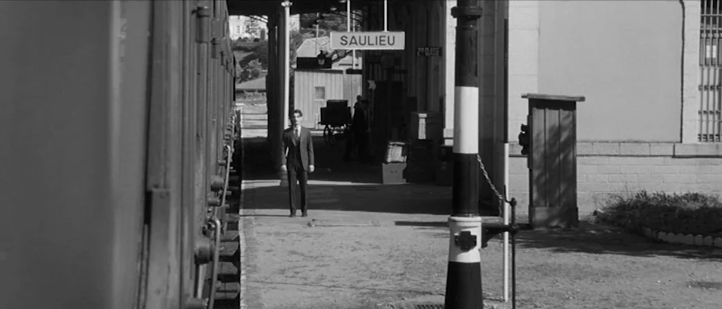 Frantz (2016) movie still: fullbody — A quiet train platform in Saulieu features a man standing near a stationary train. The platform includes…