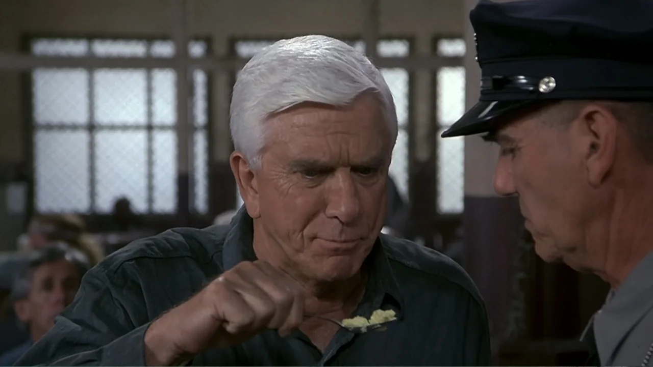 Naked Gun 33⅓: The Final Insult (1994) movie still: medium — A prison dining hall with grated windows and utilitarian interior architecture. An…