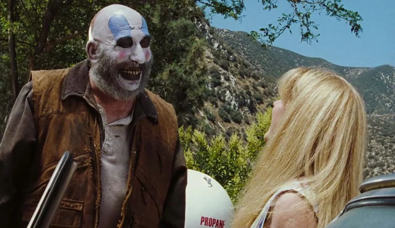 The Devil’s Rejects (2005) movie still: medium — A rugged mountain landscape with dry brush and trees serves as the outdoor backdrop. A man wearing…