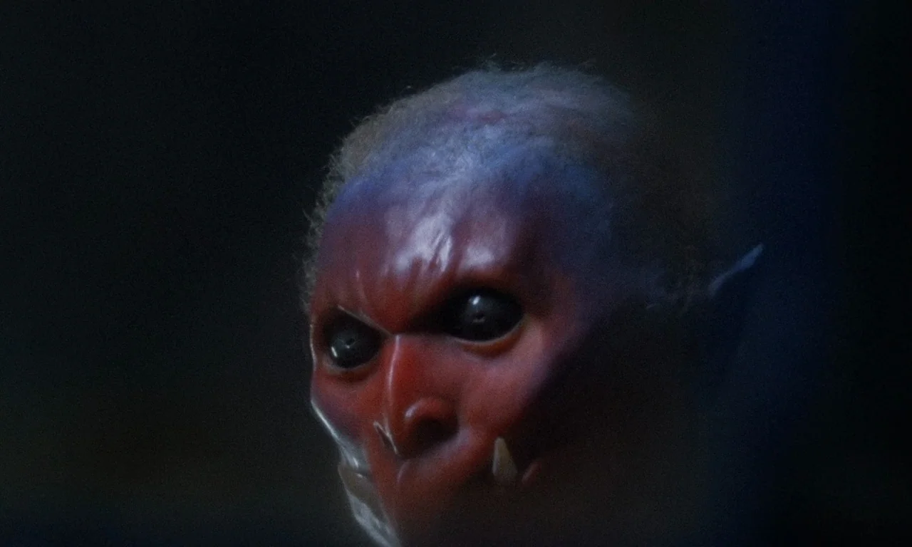 The Church (1989) movie still: closeup — A dark, abstract void serves as the backdrop for a monstrous facial feature. The creature stares intently…