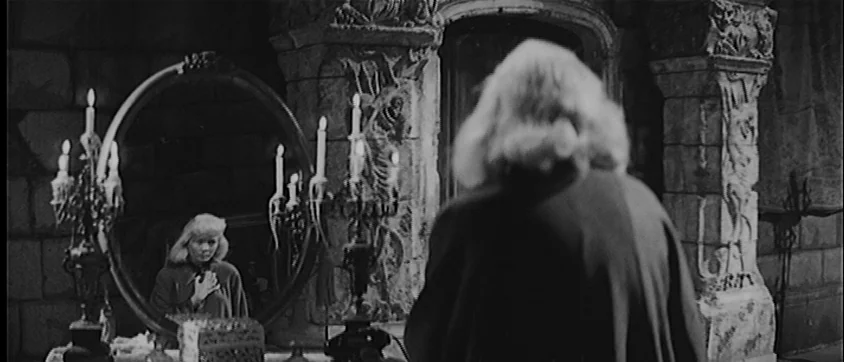 I Vampiri (1957) movie still: medium — A stone chamber with gothic architectural details and ornate carvings in the walls. A woman stands in front…