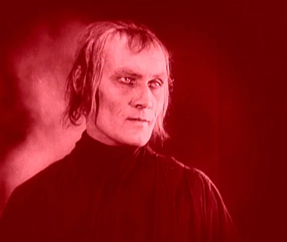 Destiny (1921) movie still: closeup — A man stands against a dark, featureless void. The subject gazes towards the right side of the frame.