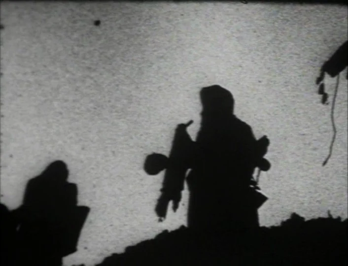 Begotten (1989) movie still: medium — A bright, overexposed outdoor landscape with heavy grain texture throughout the frame. Two dark silhouettes of…